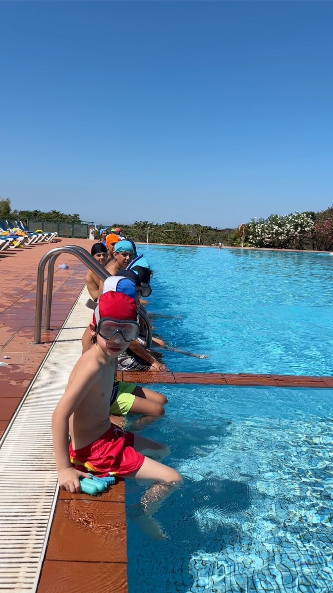 Bambini seduti a bordo piscina con maschere da sub al Multisport Camp