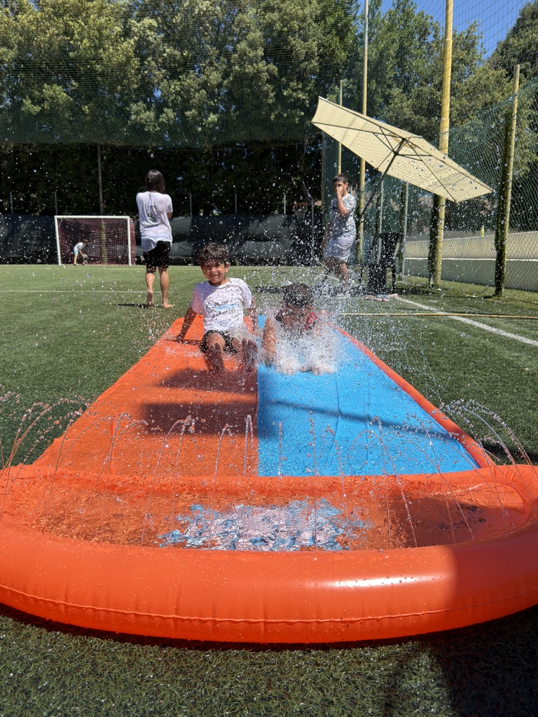 Bambini che giocano sullo scivolo gonfiabile ad acqua durante il PlayGround Camp